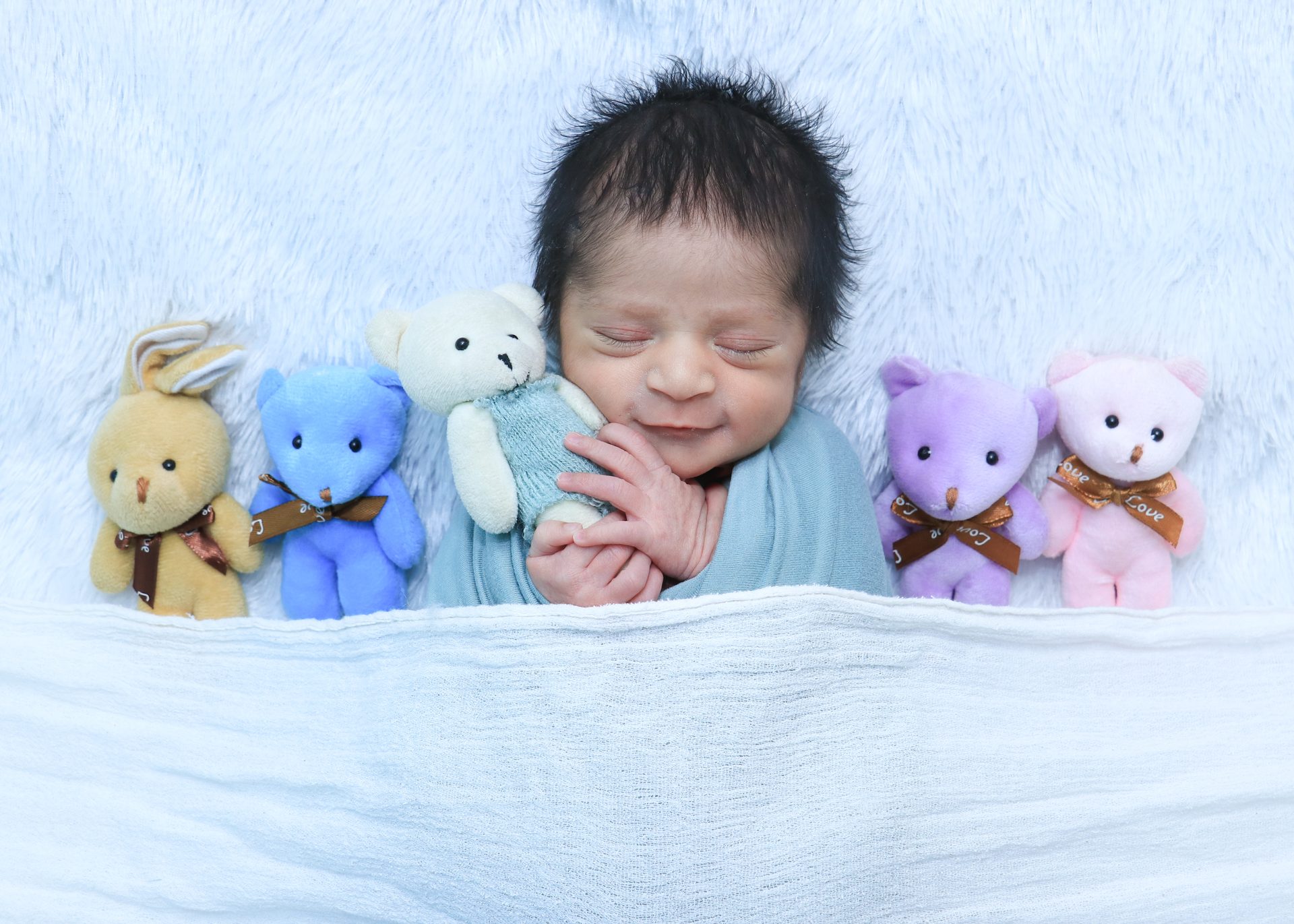 Newborn - baby with teddy bears smiling